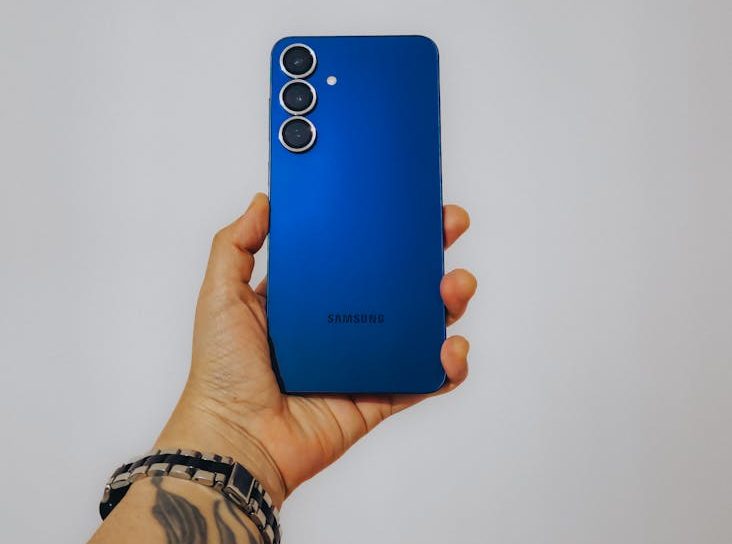 Tattooed hand holding blue phone